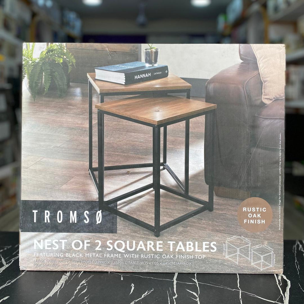 Tromso Nest of 2 Square Tables in Rustic Oak Finish, shown in its original retail packaging box. The packaging features a lifestyle image of the two nesting tables in a living room setting.